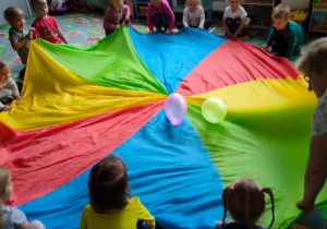Dzieci manipulują chustą animacyjną, na której znajdują się dwa balony